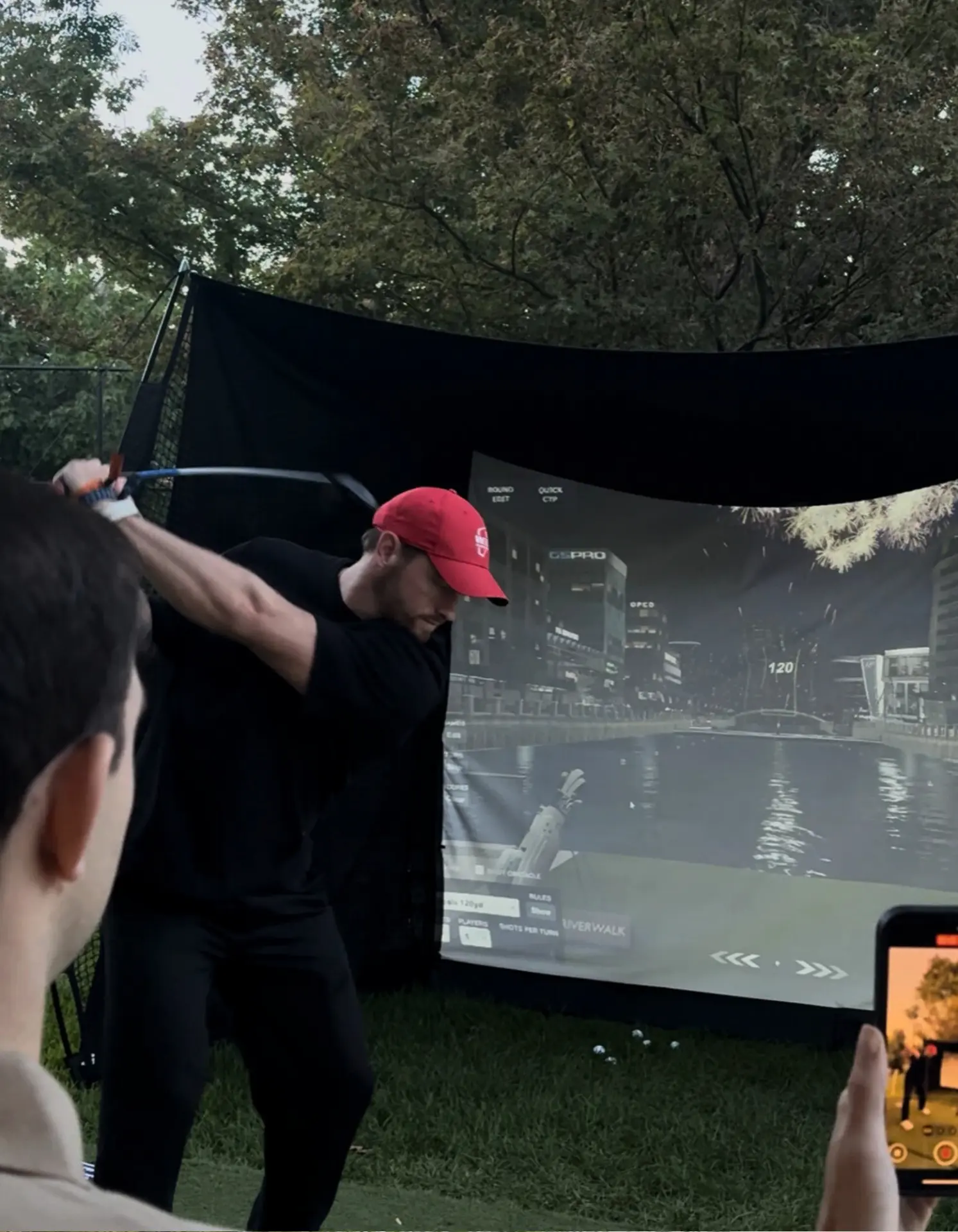 Guest playing a GSPro city course on an outdoor golf simulator hire at night in Adelaide