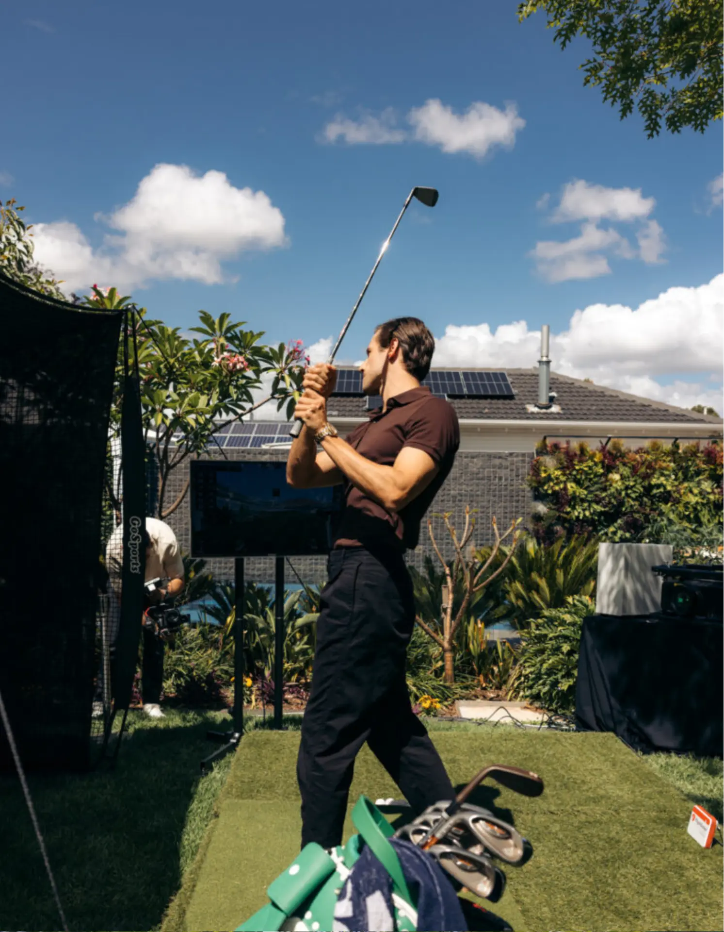 Guest taking a full swing at a backyard golf simulator hire setup in Adelaide with hitting net and outdoor screen
