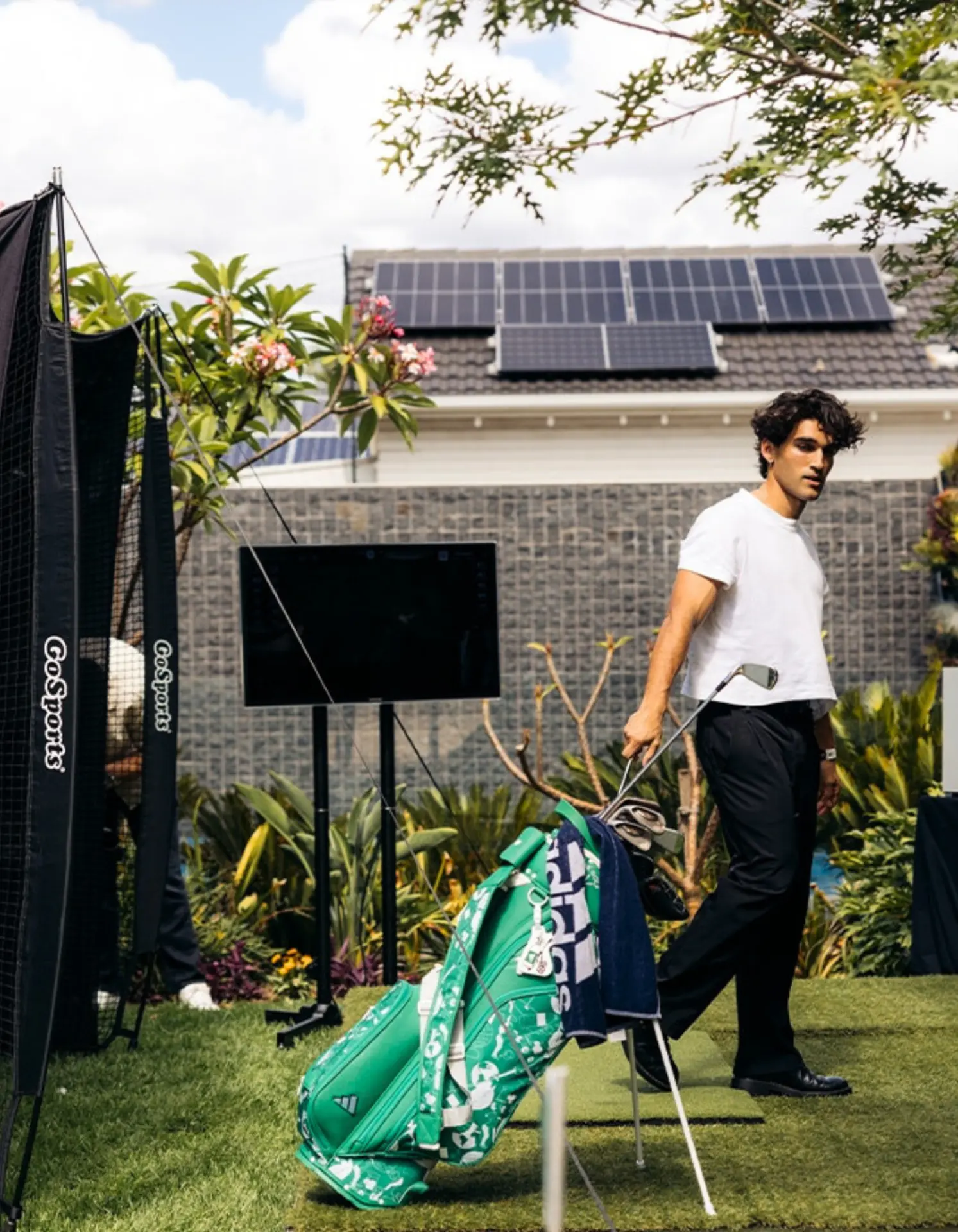 Outdoor golf simulator setup with hitting net, screen and golf bag at a backyard event in Adelaide