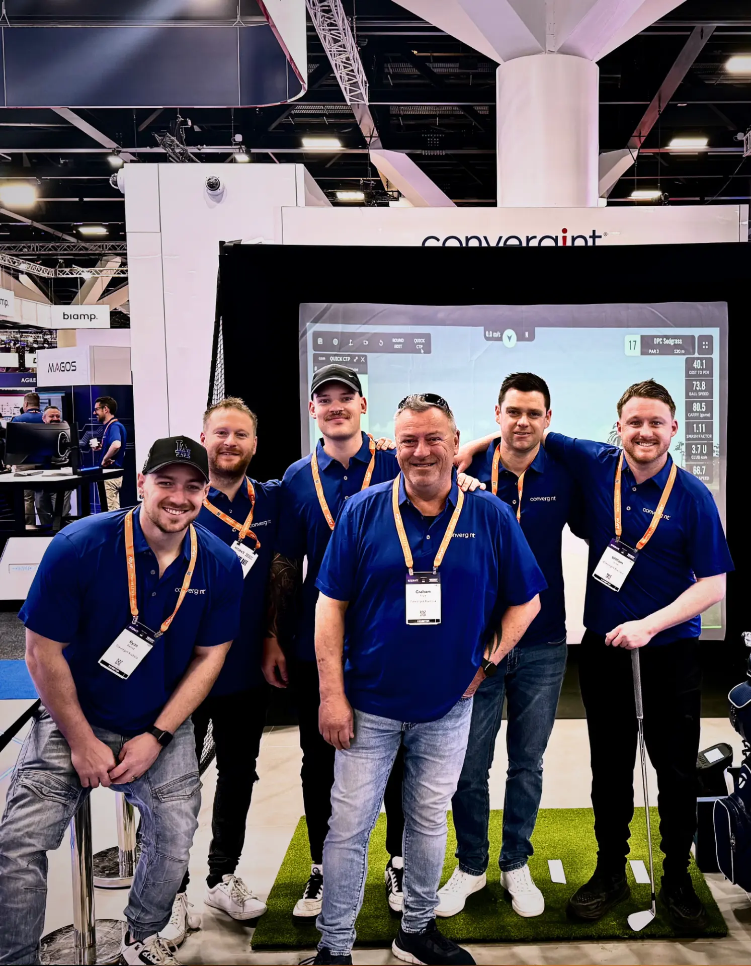 Convergint team photo in front of the Full Send golf simulator stand at the Integrate expo in Adelaide