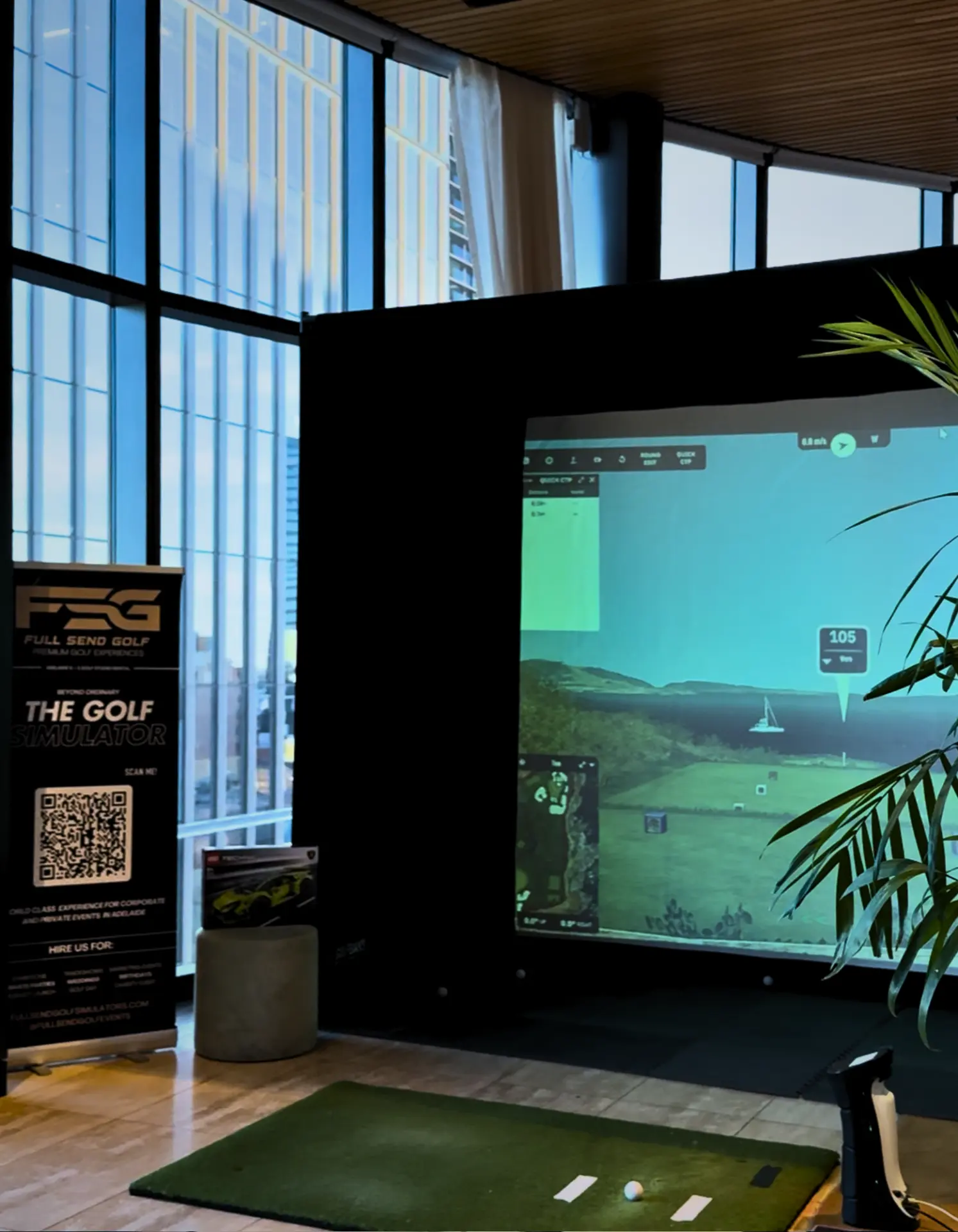 Corporate golf simulator hire setup with Full Send Golf banner inside an Adelaide venue with city views