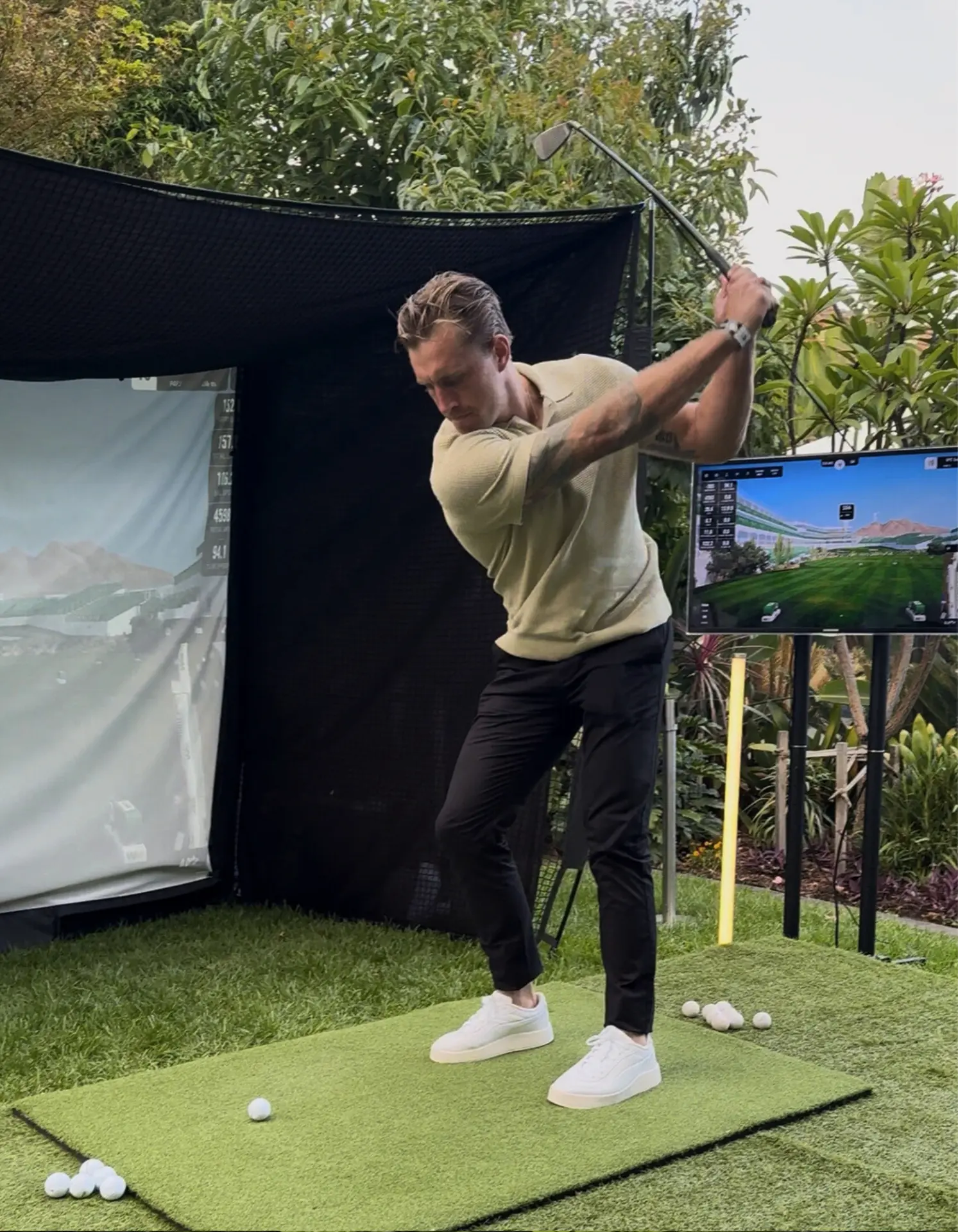Guest swinging at a backyard golf simulator with launch monitor data screens at a private Adelaide event
