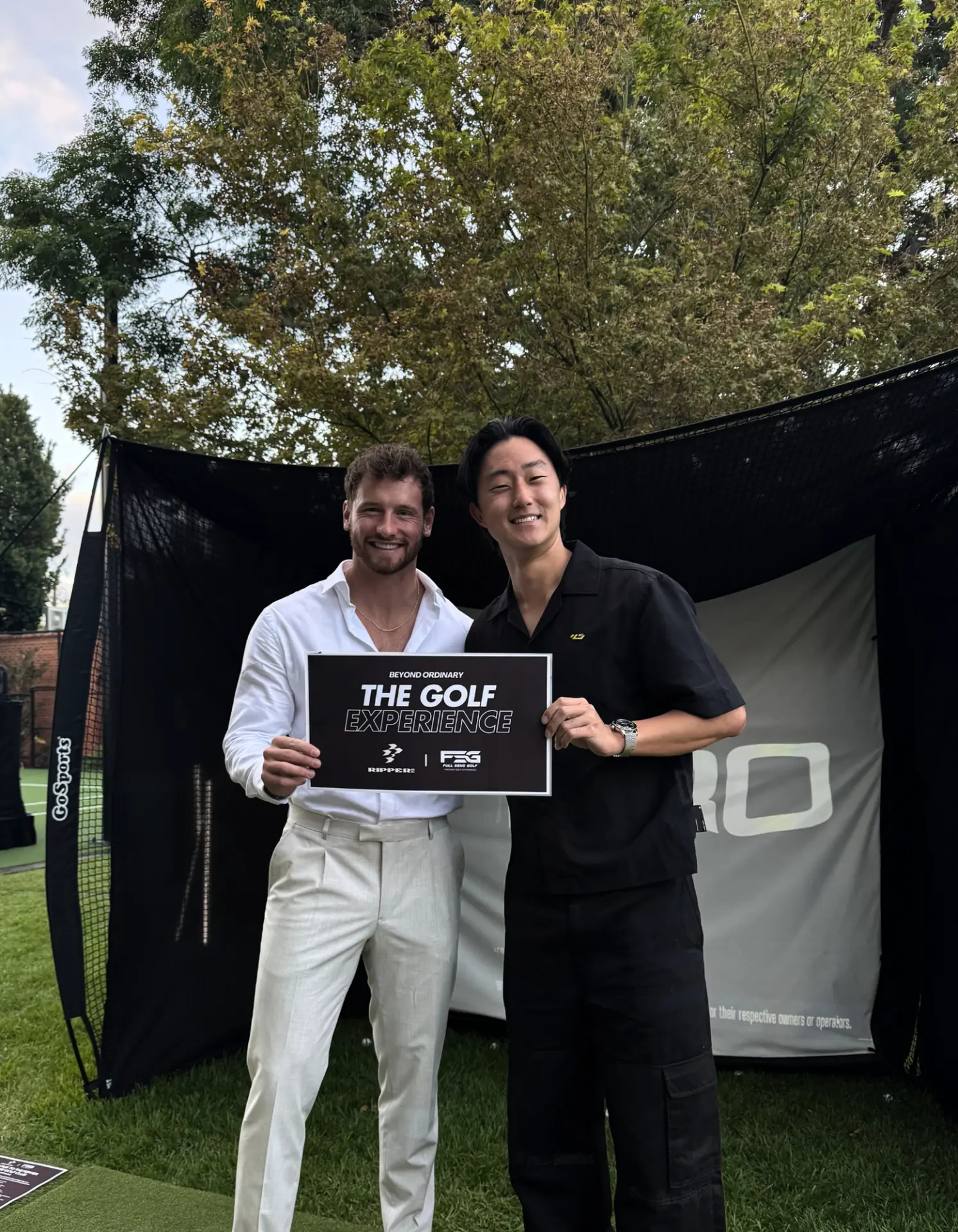 Winners holding The Golf Experience sign in front of the Full Send hitting bay at a garden event in Adelaide
