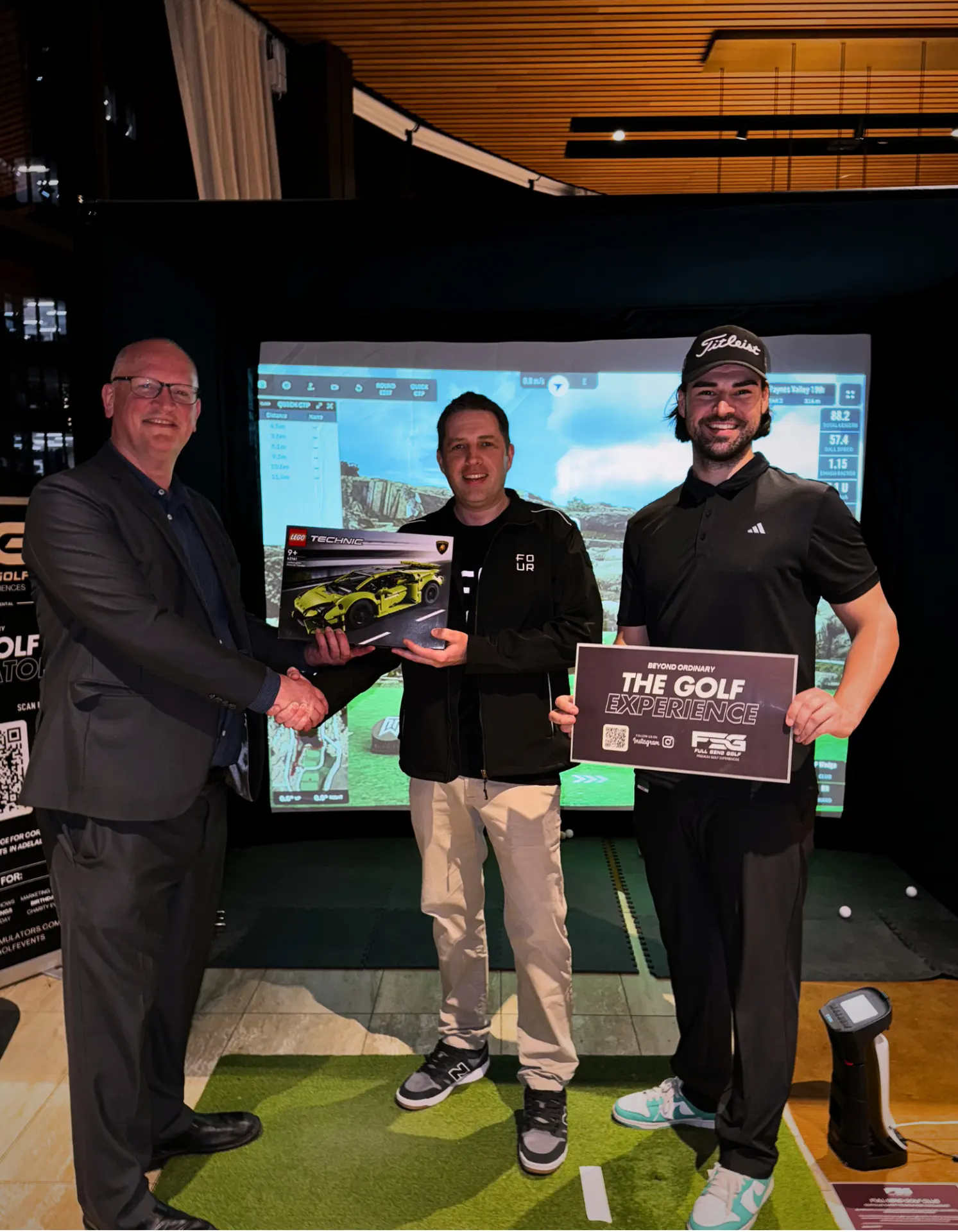 Prize presentation at The Golf Experience with a LEGO Lamborghini trophy beside the Full Send golf simulator in Adelaide