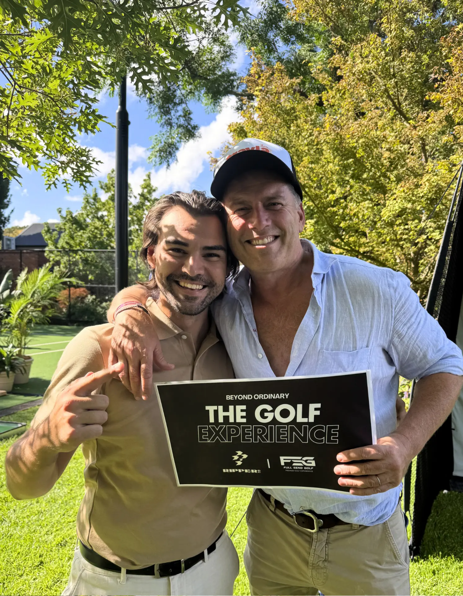 Guests smiling with The Golf Experience sign at a private garden event in Adelaide