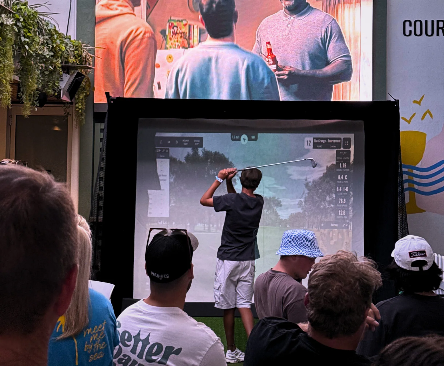 Guest playing The Tee Box golf simulator while a crowd watches at an Adelaide event
