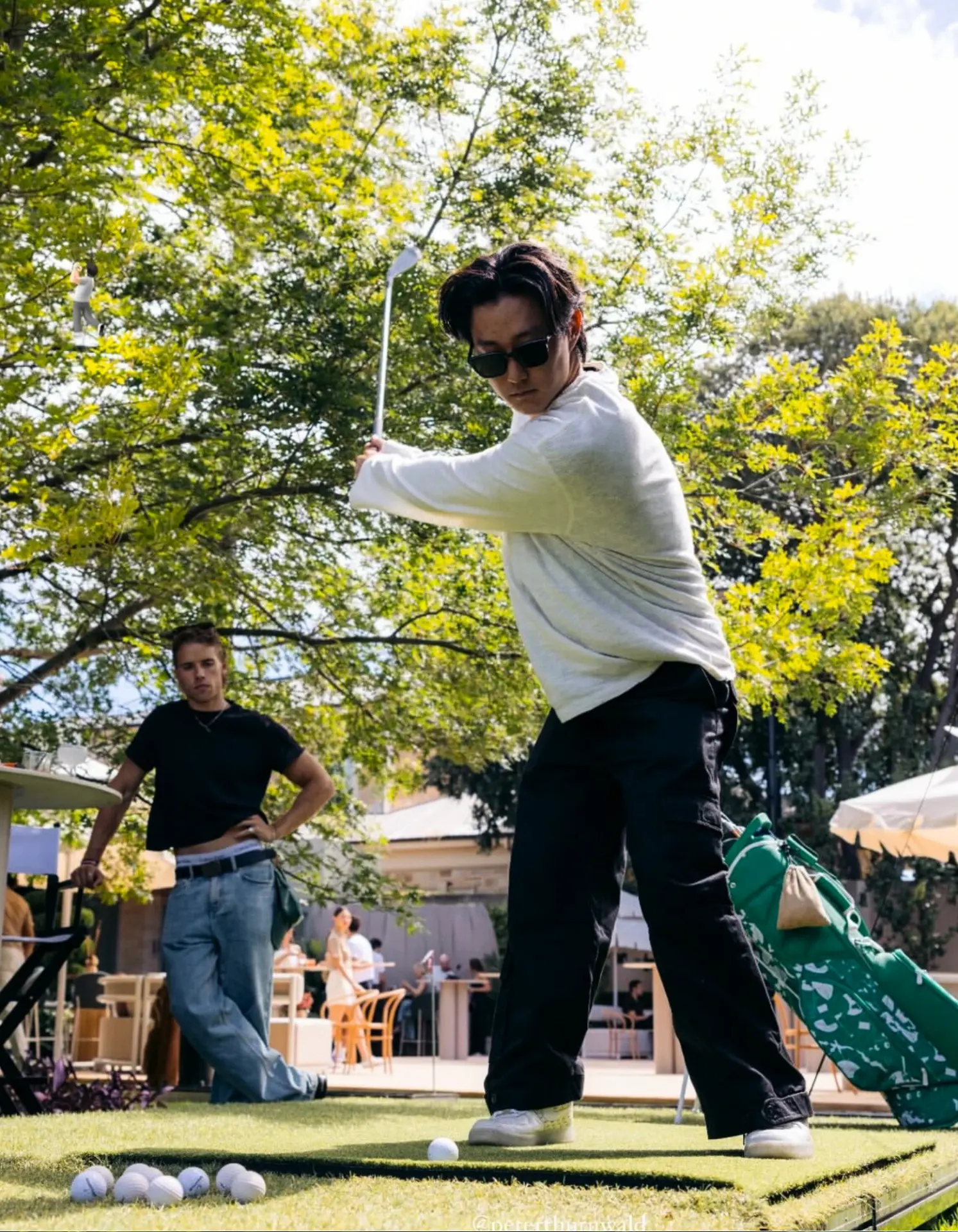 Guest mid-swing on a garden party golf simulator hire setup in Adelaide with spectators watching