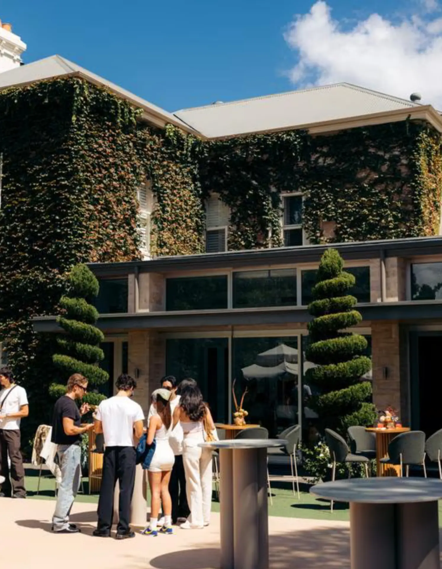 Guests mingling on the lawn of an ivy-covered private estate at a golf event in Adelaide