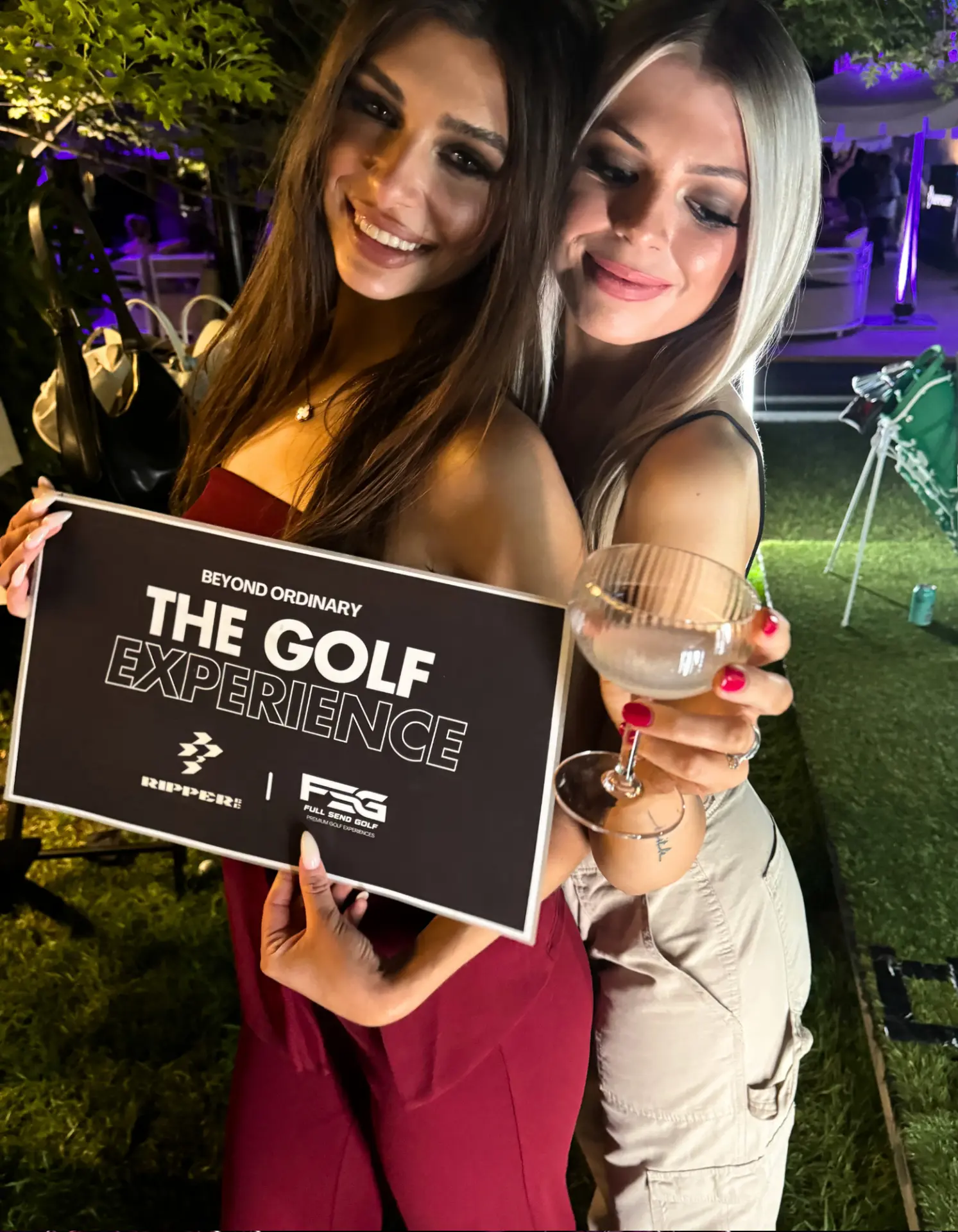 Guests celebrating with a The Golf Experience sign and cocktails at a night-time event in Adelaide