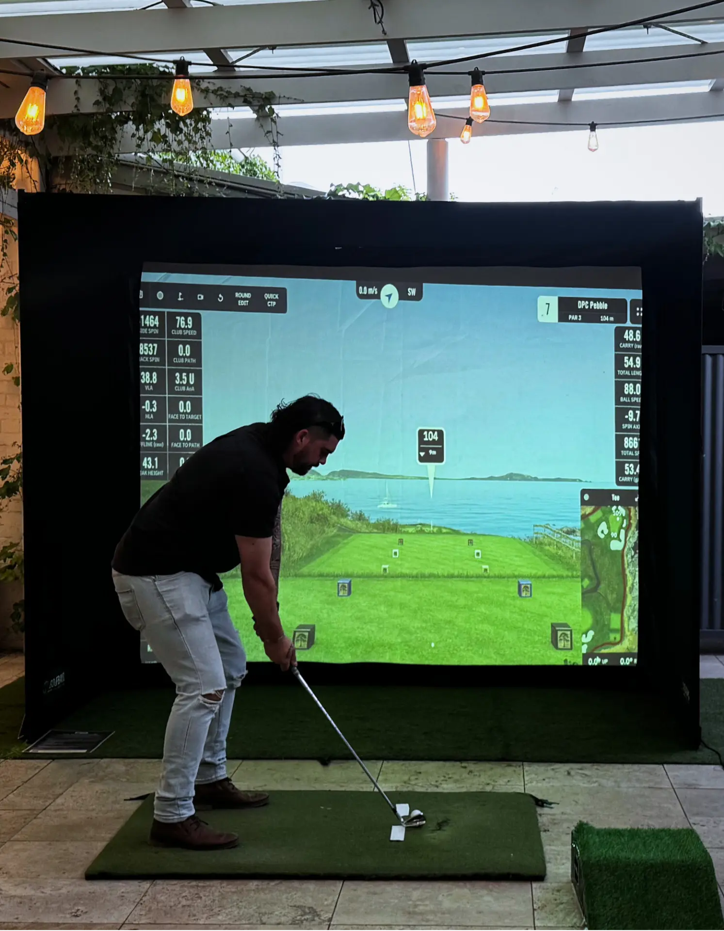 Guest playing Pebble Beach on a golf simulator at an Adelaide party under festoon lights