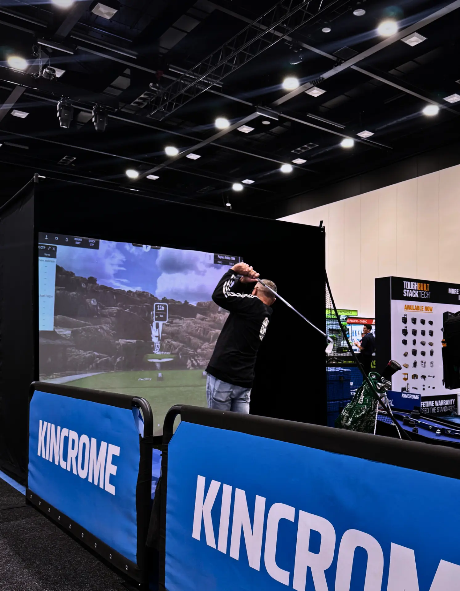 Brand activation guest swinging on a Full Send golf simulator behind Kincrome branded barriers in Adelaide