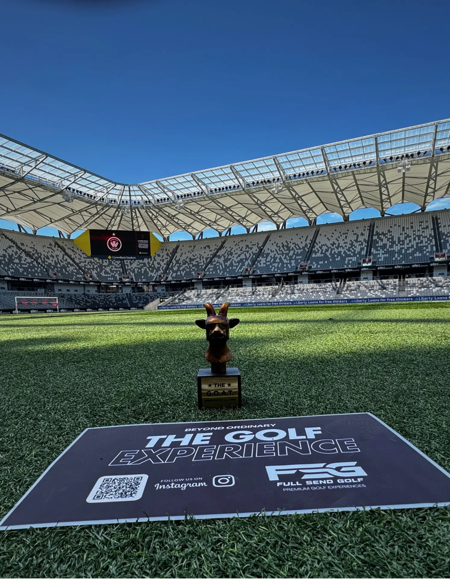 The Golf Experience activation on the stadium pitch with the G.O.A.T. trophy and Full Send Golf signage